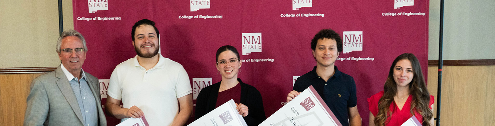 A man standing next to four scholarship recipients, two men and two women